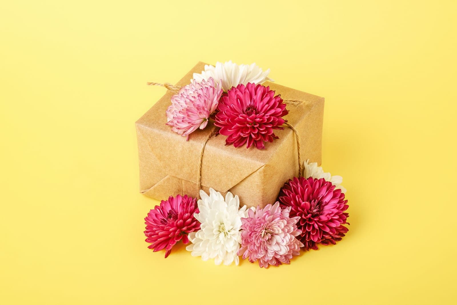 A gift box decorated with red and white flowers on a yellow background