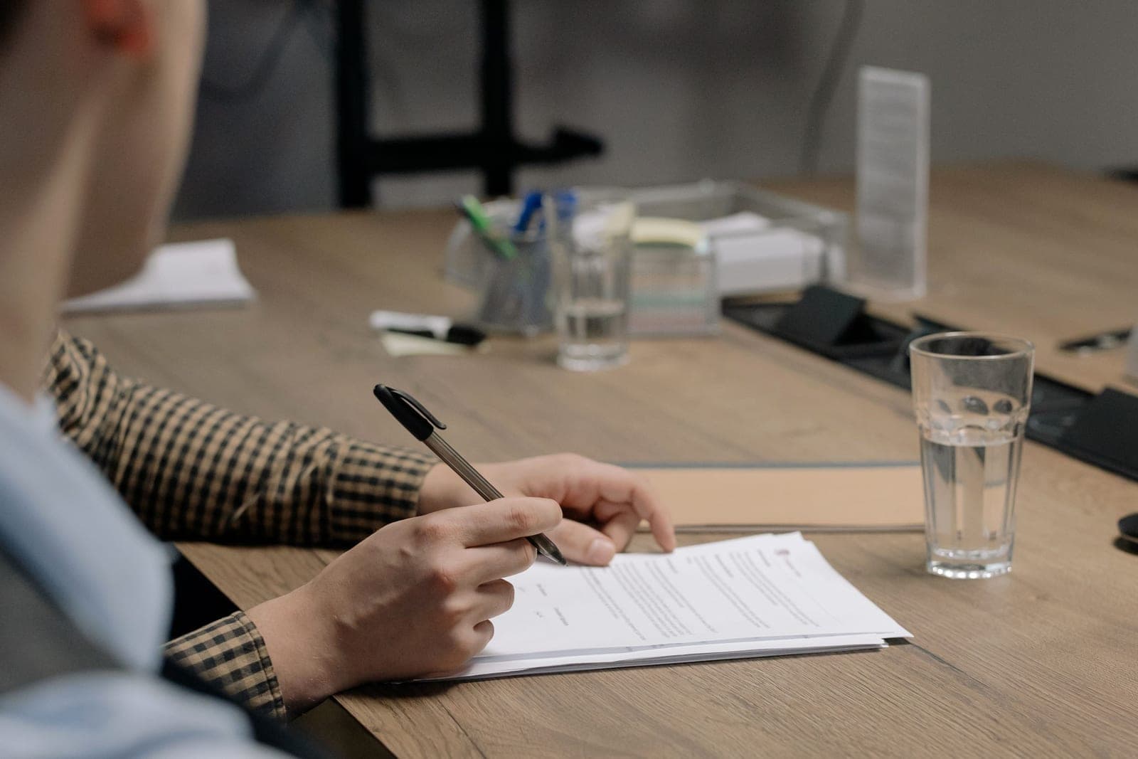 A person signing a document at a wooden table