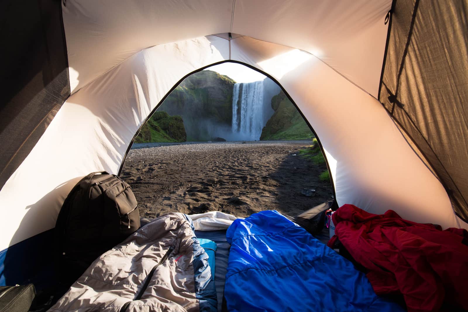 The view from inside a tent toward a waterfall