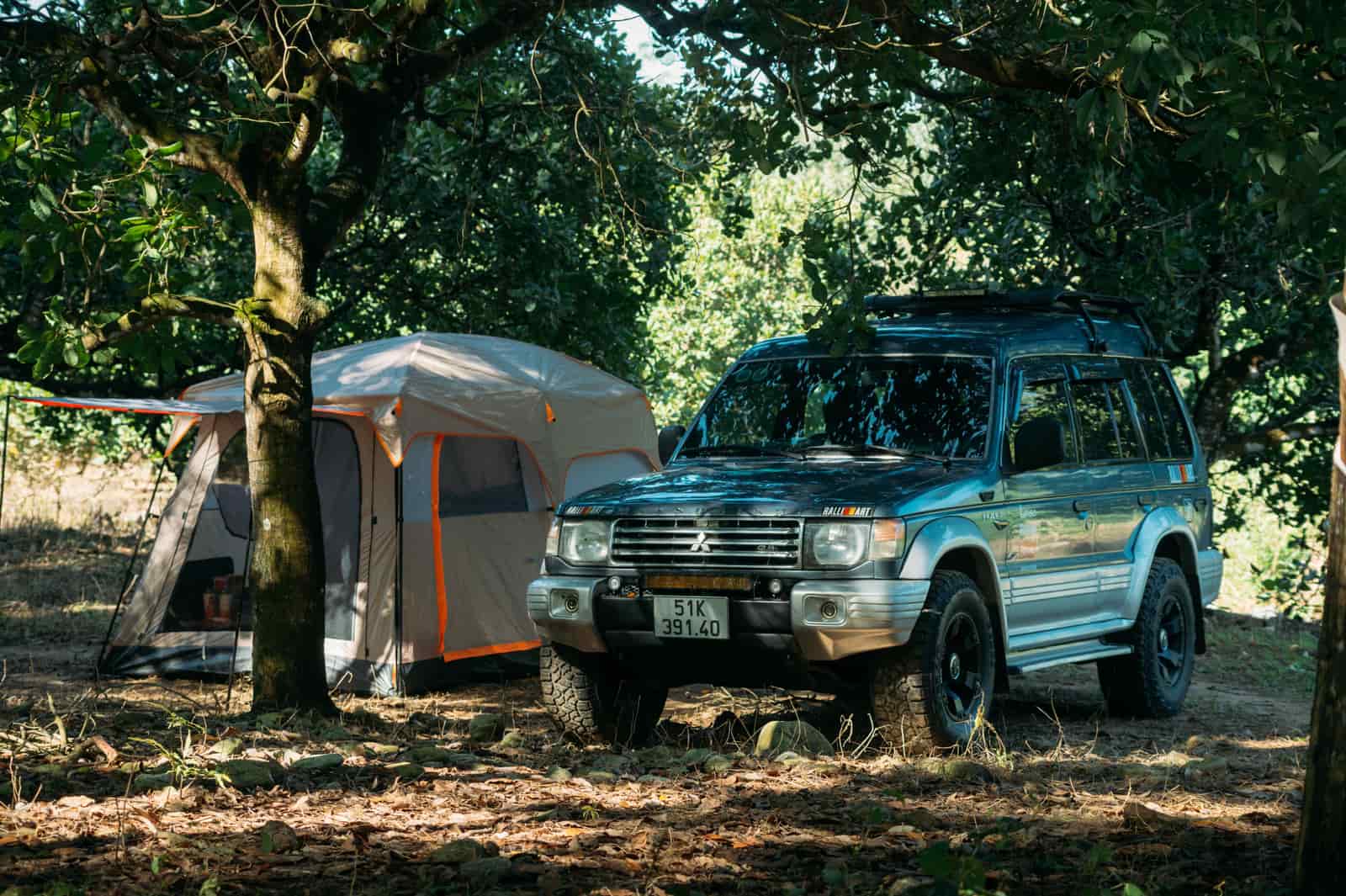 An SUV parked beside a tent in a forest