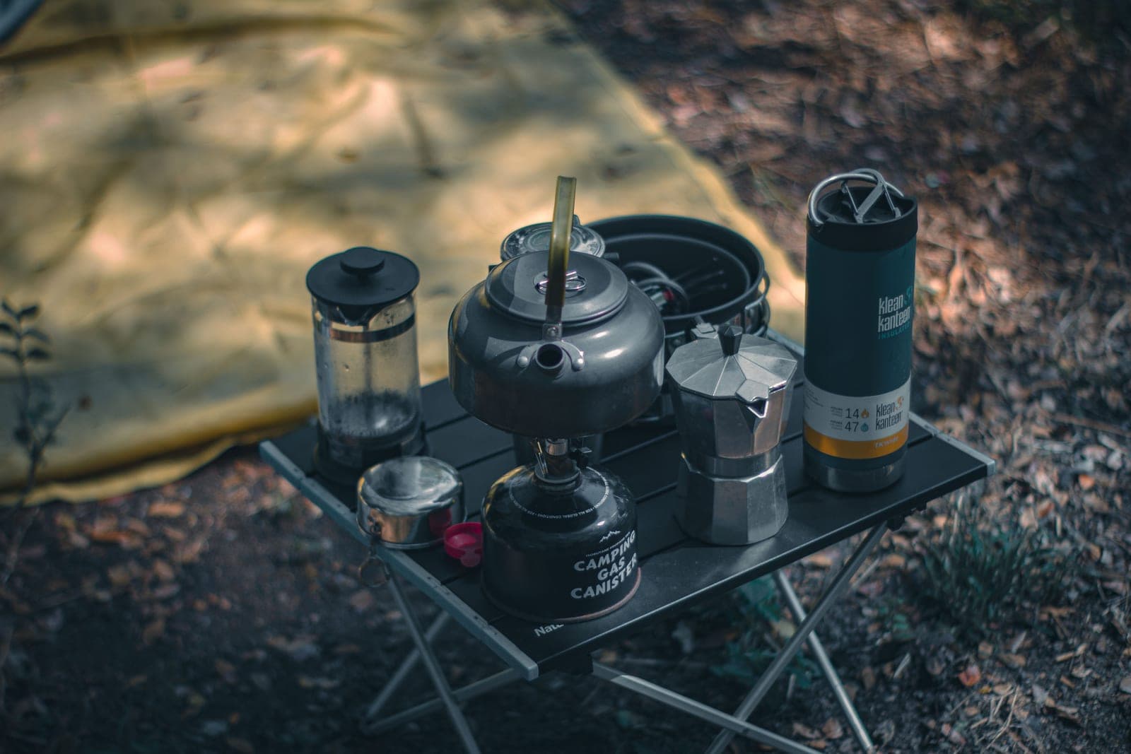 Coffee-making gear set up outdoors beside a tent